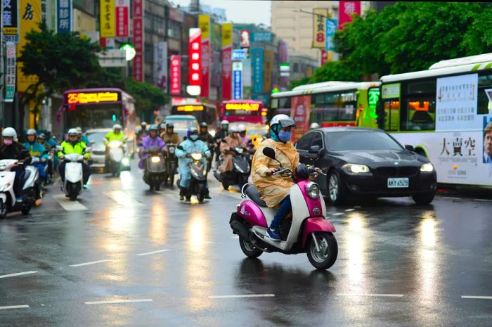 A bustling scene of scooters, cars, and buses navigating through the rain in Taipei, Taiwan