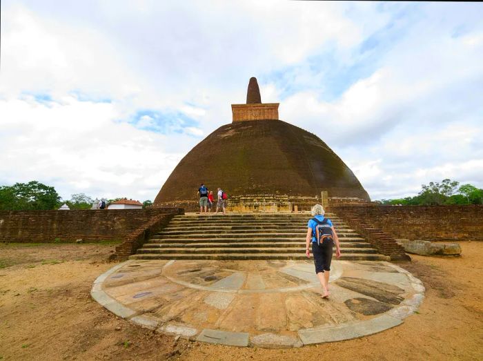 Visitors walking around an ancient stupa, a large domed structure