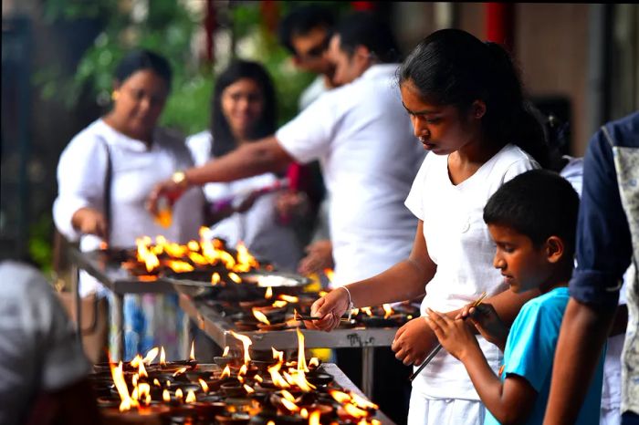 Sri Lankan Buddhists congregate at a temple, surrounded by burning incense