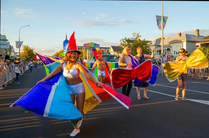 Individuals in colorful attire revel and dance in the streets