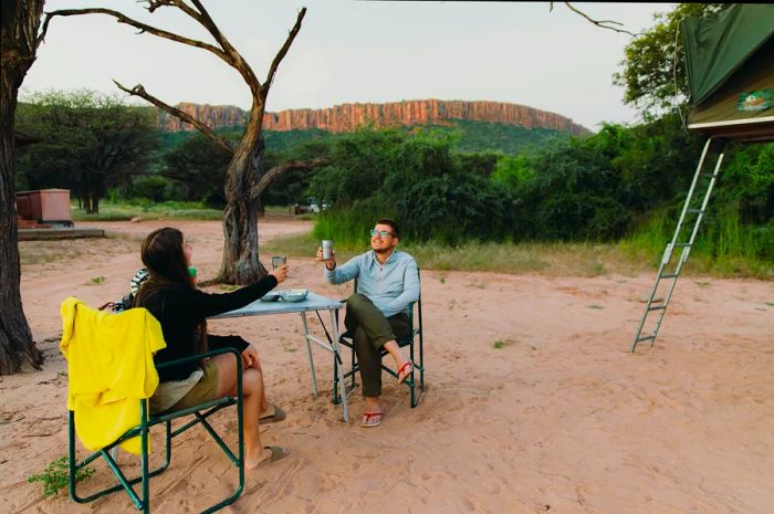 Two adventurers toast at their campsite in Namibia