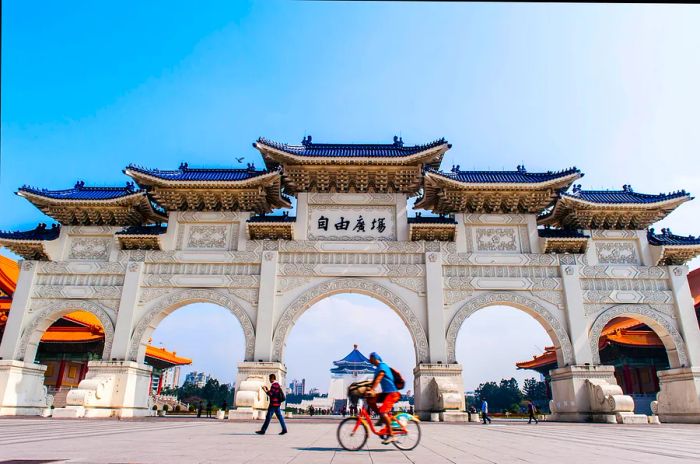 A grand white multi-arched gateway with a cyclist passing by