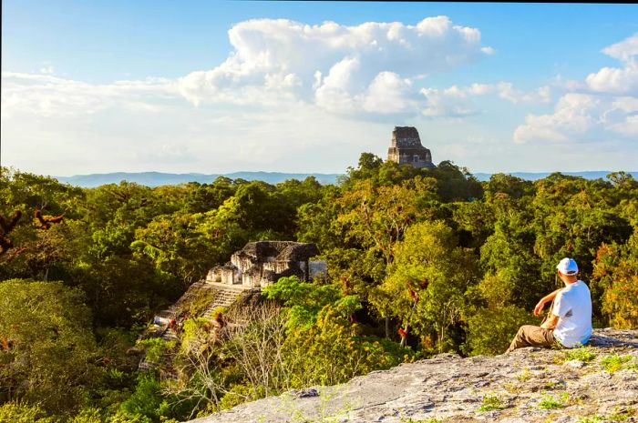 A tourist enjoying the breathtaking views of Tikal's ruins from Temple IV, Guatemala