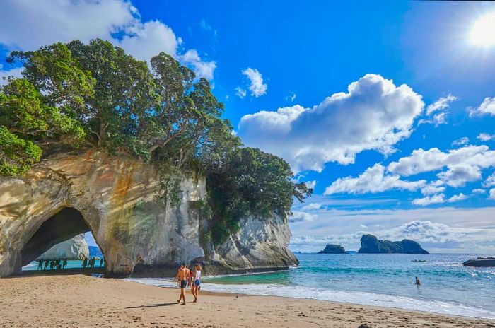 A prominent rock archway stands out against a sandy beach