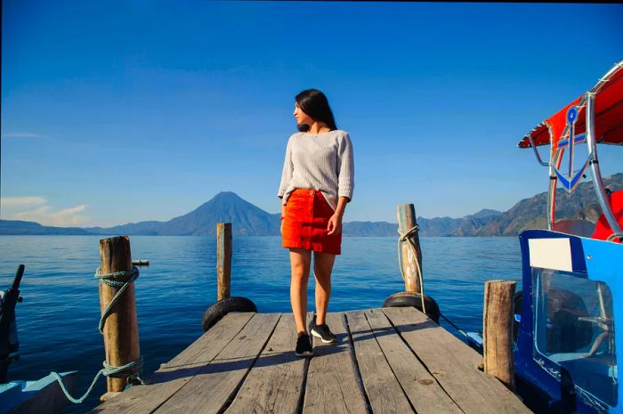 A Hispanic woman stands on a pier by Lake Atitlán in Guatemala.