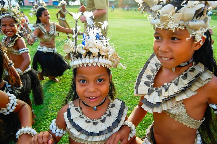 Children in traditional Fijian attire beam for the camera