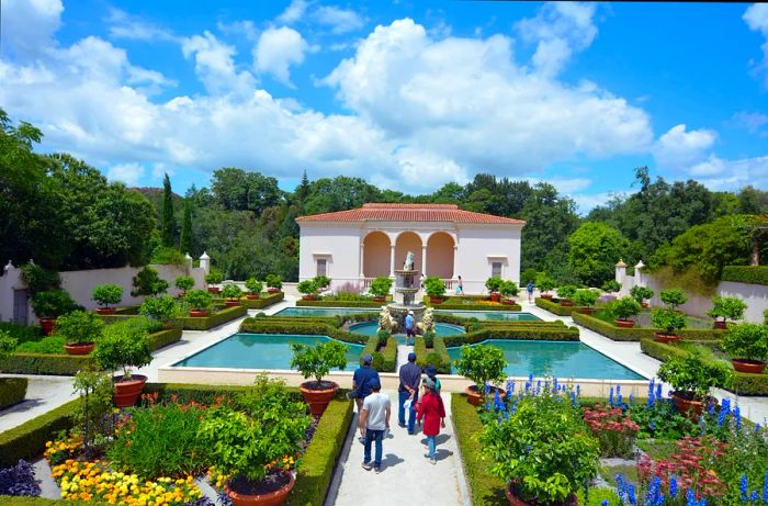 Tourists wandering through an Italian-inspired garden, featuring individual flower beds bordered by low hedges