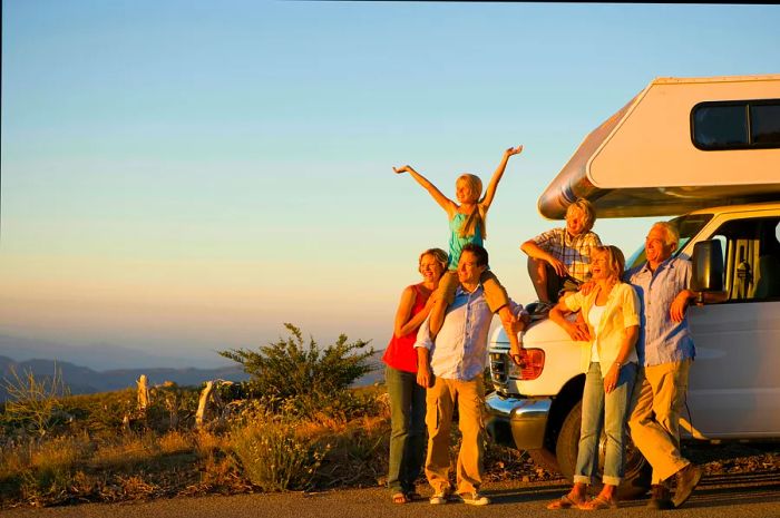 A family of three generations gathers by their motor home on the roadside as dusk settles in.