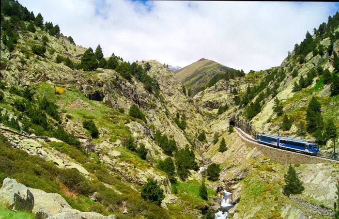 A train traverses the Vall de Núria Hiking Trail in Catalonia, Spain.