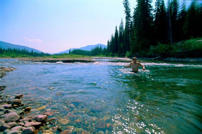 A young man splashes in a mountain stream within Jewel Basin, Montana