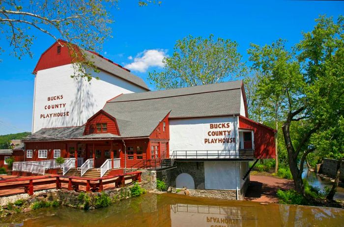 The barn-like red and white theater by the water is the Bucks County Playhouse, located in New Hope, Bucks County, Pennsylvania, USA. State Theater of Pennsylvania.