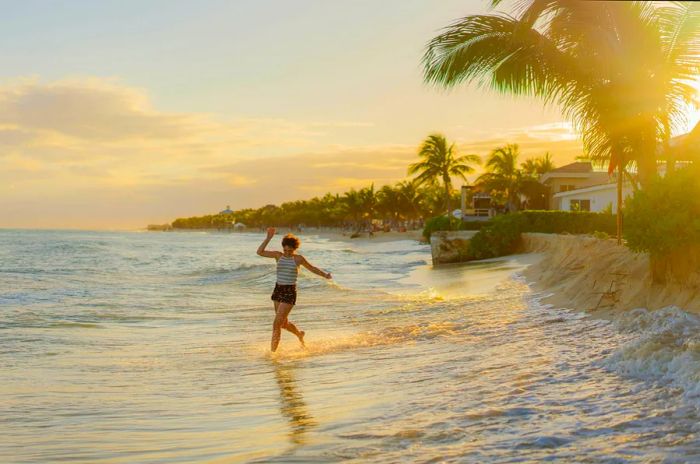 A joyful young woman dashes into the water at a beach in Tulum, Mexico