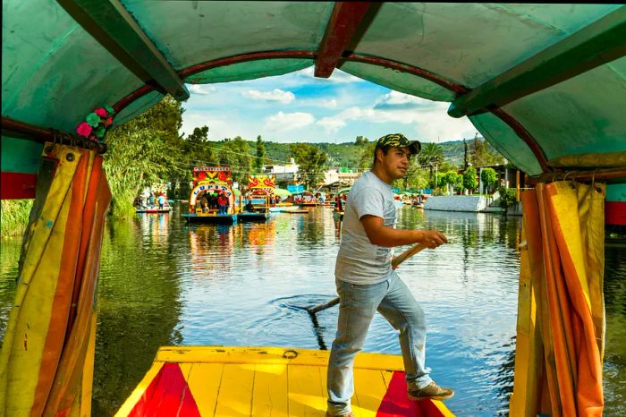 A trajinera boat navigating the canals and floating gardens of Xochimilco in Mexico City, Mexico