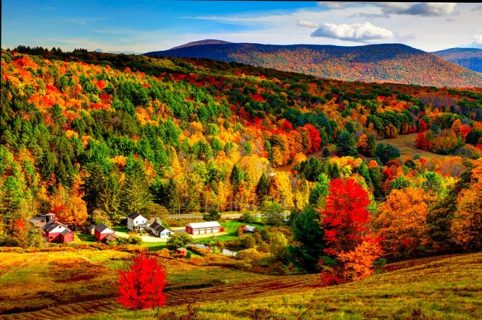 Fall foliage paints a charming Massachusetts valley, with a quaint village peeking through; New England fall foliage road trip