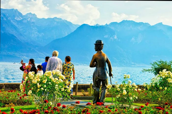 A statue of Charlie Chaplin in Vevey overlooks tourists enjoying the view of Lake Geneva