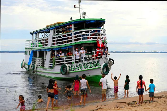 In Manaus, Amazonas, Brazil, children from the Iranduba riverside community greet a boat carrying “Santa Claus.”