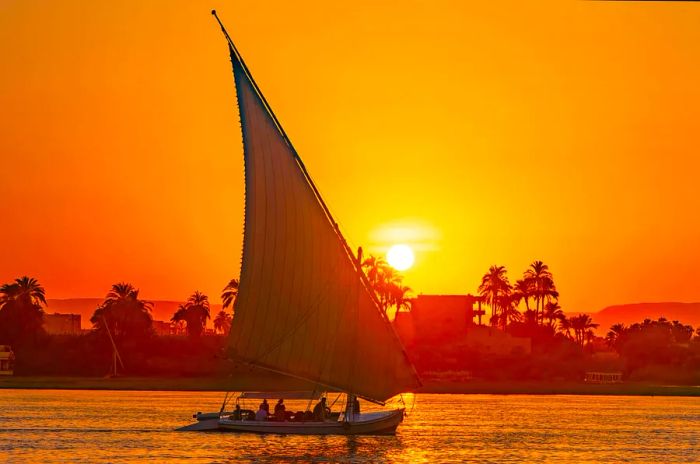 A felucca glides along the Nile at sunset in Luxor, Egypt