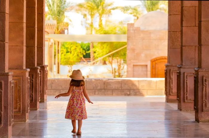 A young girl strolls through a portico lined with columns in Sharm El Sheikh, Egypt.