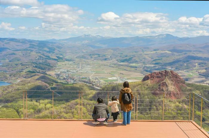 A small family group gazes over an expansive landscape from a scenic viewpoint