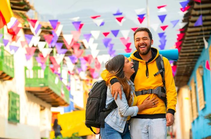 A couple shares a joyful embrace while strolling down a vibrant street in Colombia.