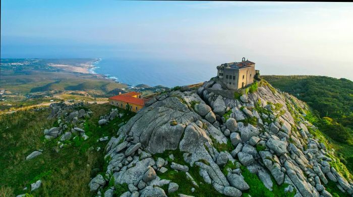 An aerial view showcases Santuário da Peninha, perched on a mountain along the Sintra coast.