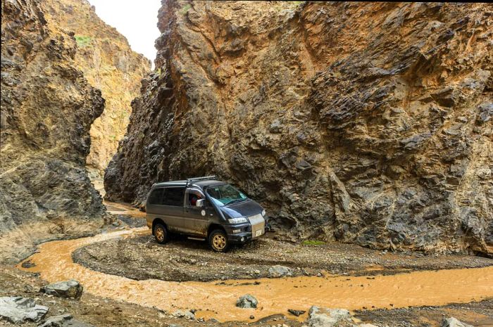 An off-road vehicle navigates a rocky gorge in the mountainous terrain of the Gobi, Gurvan Saikhan National Park, Mongolia