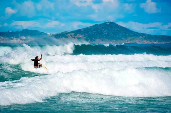 A surfer glides through a frothy wave in Cabo Frio, Rio de Janeiro, Brazil.