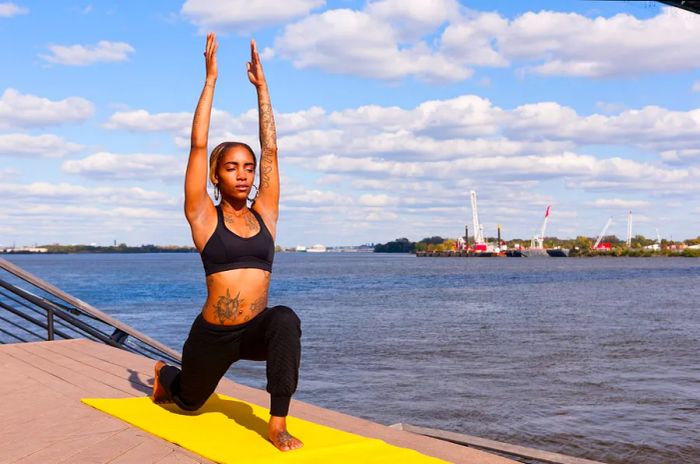 A beautiful Black woman practicing yoga by the river in Philadelphia, PA.