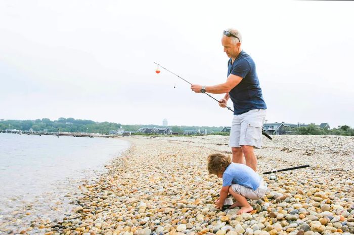 A father and son enjoy fishing on a pebbly beach in Montauk, New York.