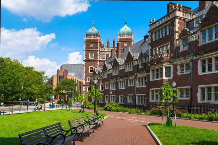 A large brick university building nestled beside a green campus