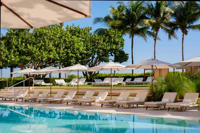 A swimming pool adorned with a pristine line of cream-colored sun loungers.