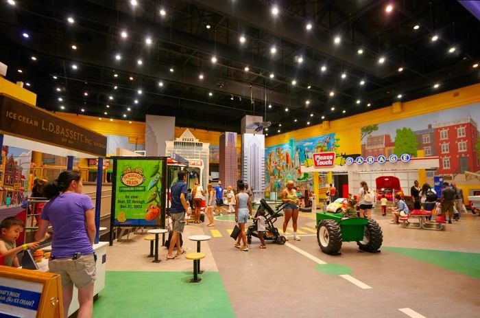 Families with young children engage in play on trucks and explore exhibits at a museum.