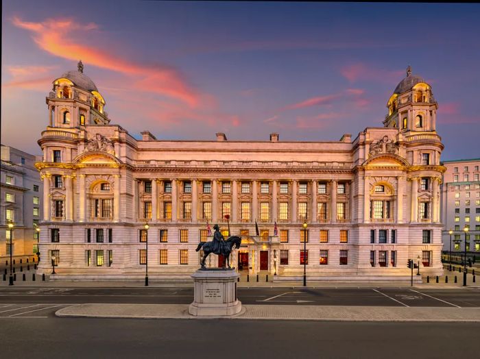 The facade of an elegant hotel building featuring domed turrets at each end during sunset.