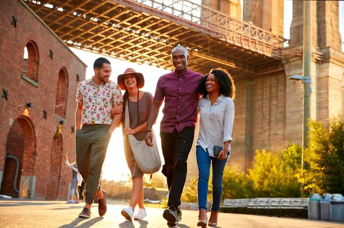 Four friends strolling and enjoying themselves beneath the Brooklyn Bridge.