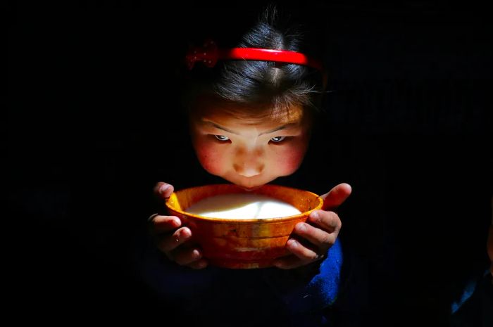 Mongolian girl enjoying airag, a traditional milk drink