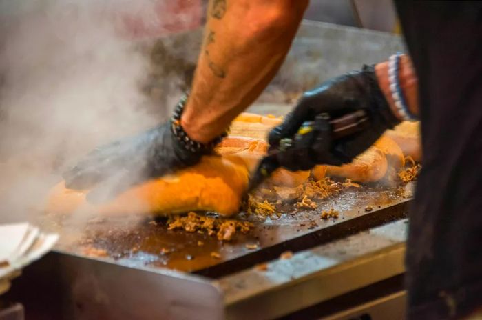 Thinly sliced rib-eye steak sizzling on a griddle, preparing a classic Philly cheesesteak