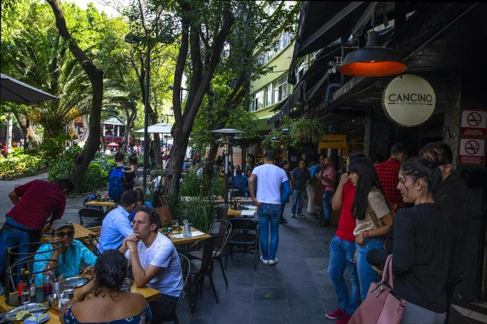 Patrons enjoying meals at outdoor tables in the Roma neighborhood of Mexico City