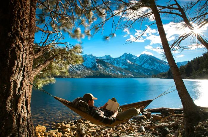 A male backpacker lounging in a hammock by a lake in a U.S. park