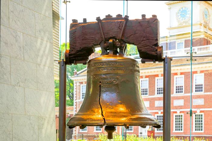 A prominent bell with a crack running through it, displayed in a glass enclosure