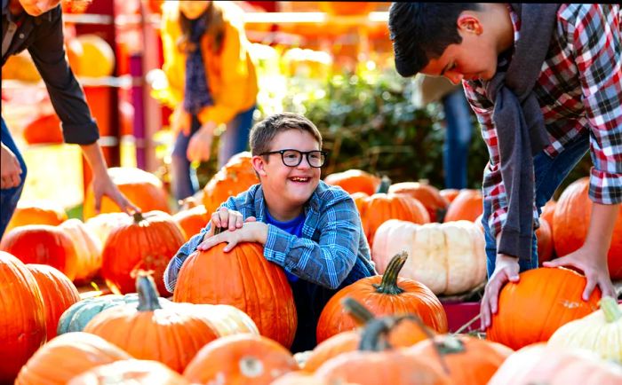 A boy with Down syndrome joyfully enjoying a pumpkin patch