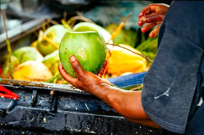 A coconut seller in St. Lucia holds a freshly cut coconut