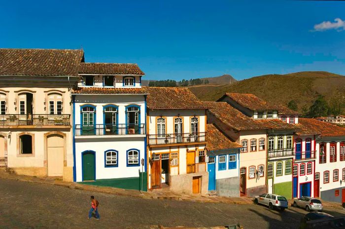 A woman strolls by vibrant colonial buildings in Ouro Preto, Brazil.