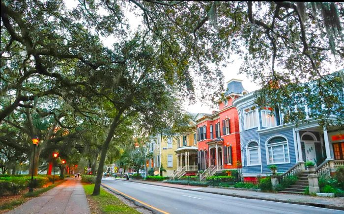 A row of colorful historic homes illuminated at dusk in Savannah, Georgia.