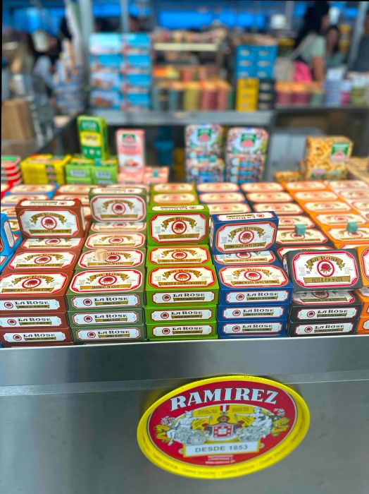 Piles of sardine tins displayed at a bustling market stall