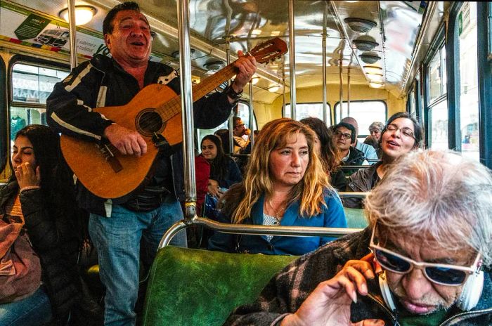 Passengers on a bus in Central Valparaiso, a UNESCO World Heritage Site in Chile, are entertained by a singer with a guitar, eliciting mixed reactions from the audience.