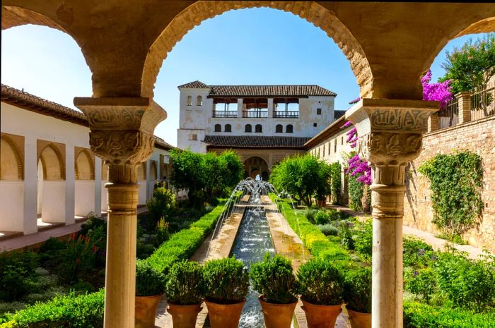 An elegant rectangular courtyard featuring stunning fountains, framed by a beautiful archway