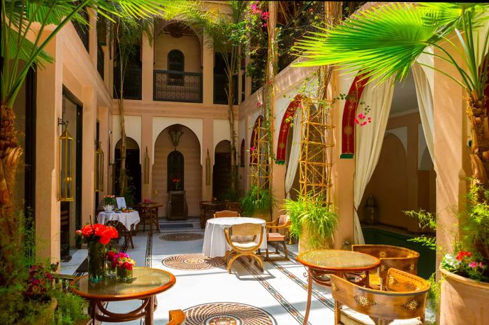 The shared space in a riad courtyard featuring chairs, tables, and greenery