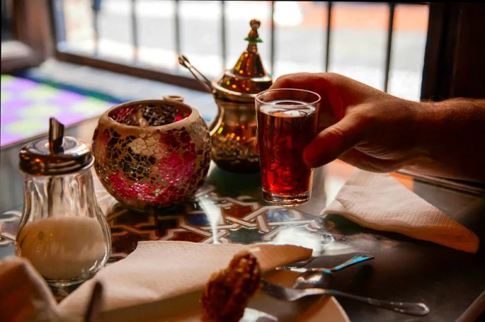 A hand cradles a glass of tea in a quaint tea shop