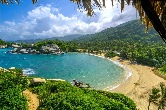 A small cove of golden sand nestled against a dense jungle.