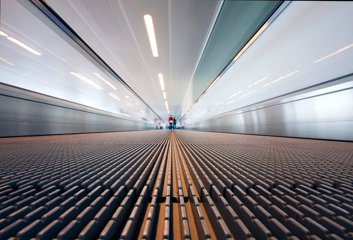 A low-angle view from the perspective of a moving walkway in a large international airport